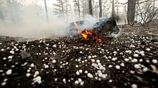 A log keeps burning as hail lies on the ground near Susanville, California. July 21, 2020