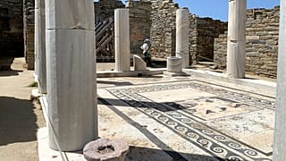 An Archaeological Service worker walks past marble columns on the island of Delos, an ancient center of religious and commercial life, in Greece, June 2020.