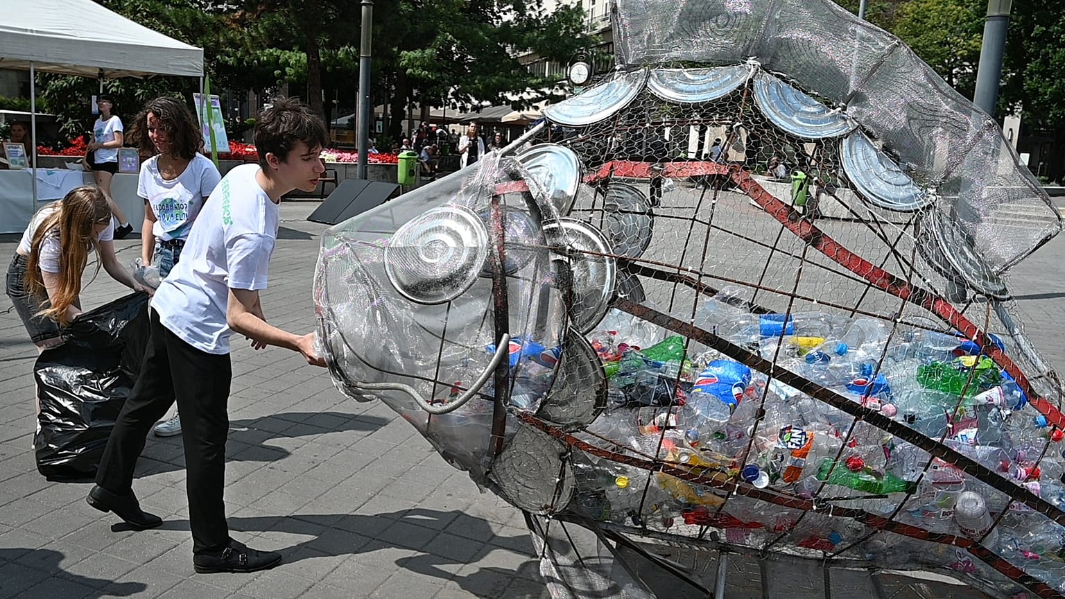 Des enfants mettent des bouteilles en plastique dan un collecteur en forme de poisson dans le centre de Budapest, le 20 juillet 2020