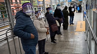Peruanos esperan la llegada de un autobús en una parada de Lima