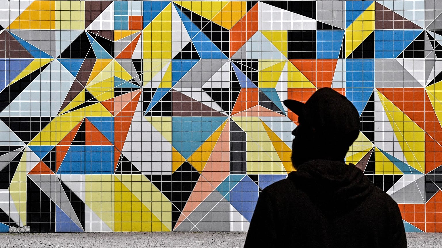 A man passes a colorful tiled mural by American artist Sarah Morris in the old town of Duesseldorf, Germany, Tuesday, July 14, 2020.