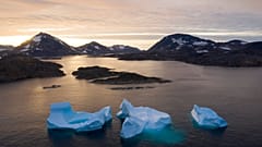 In this Aug. 16, 2019, photo, large Icebergs float away as the sun rises near Kulusuk, Greenland. 