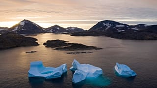In this Aug. 16, 2019, photo, large Icebergs float away as the sun rises near Kulusuk, Greenland.