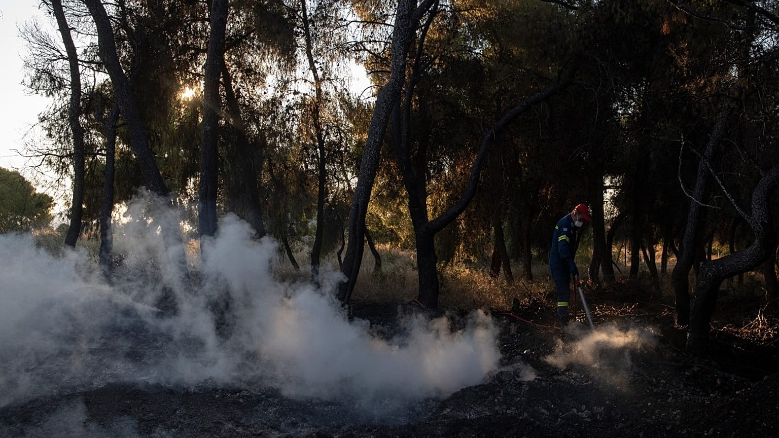 A firefighter tries to extinguish the fire near the seaside area Kechries, near Corinth, Greece,