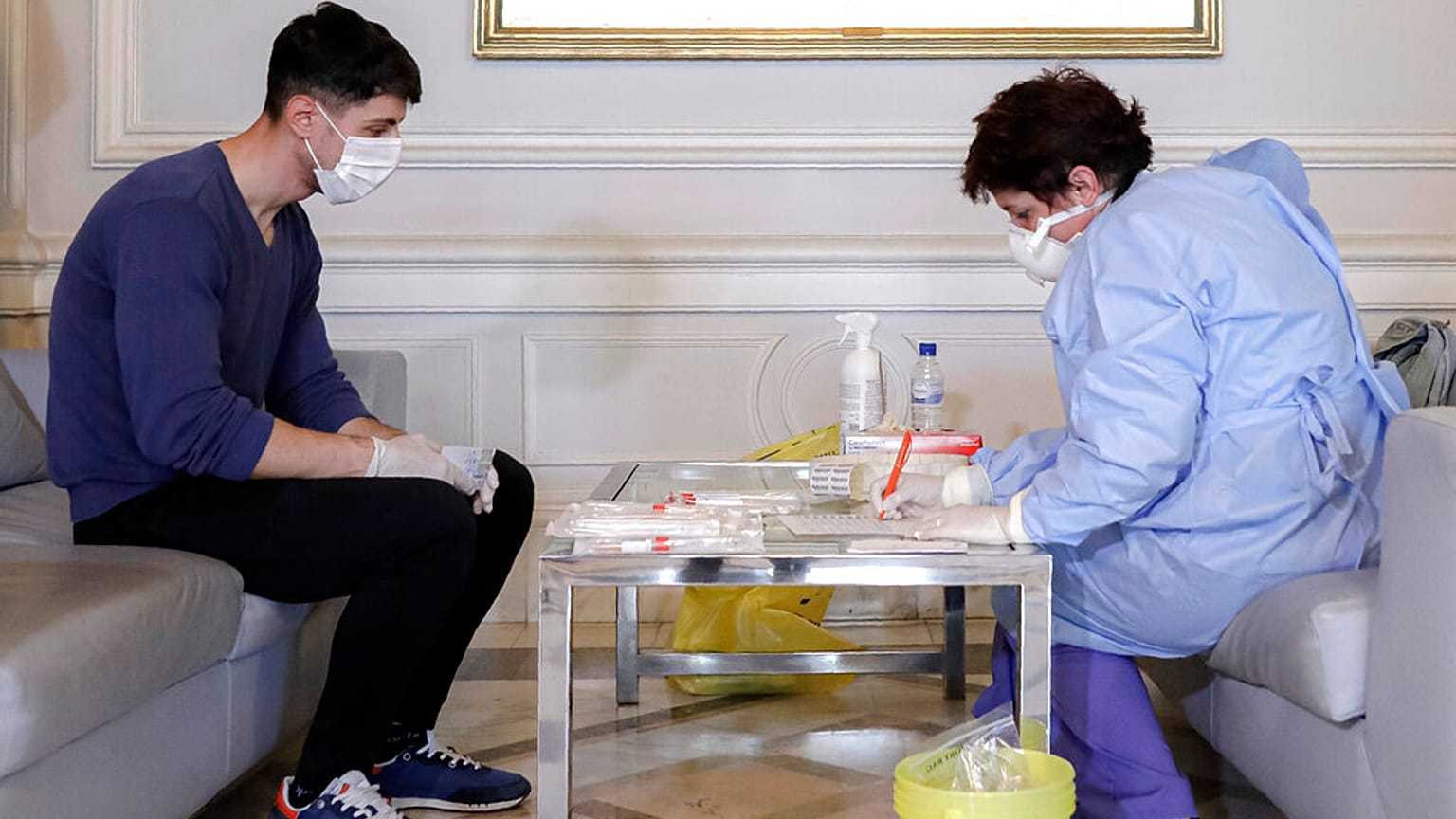 A health official takes samples for a coronavirus test from a journalist in Bucharest, Romania, March 13, 2020.