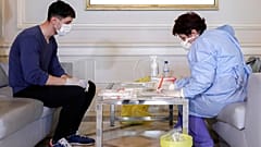 A health official takes samples for a coronavirus test from a journalist in Bucharest, Romania, March 13, 2020.