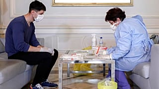 A health official takes samples for a coronavirus test from a journalist in Bucharest, Romania, March 13, 2020.