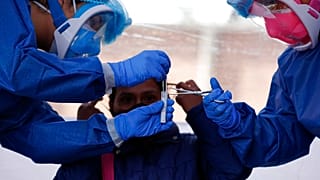 Nurse Claudia Flores Martinez, right, assists Dr. Diana Pacheco as she collects samples from a COVID-19 test, inside a mobile diagnostic tent in Mexico.