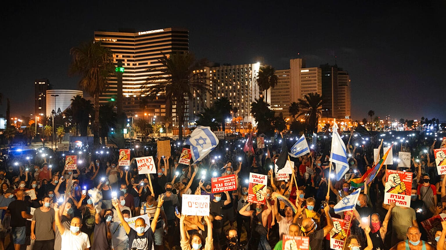 Protesters hold signs during a protest against Israel's Prime Minister Benjamin Netanyahu in Tel Aviv, Israel, on July 25, 2020 