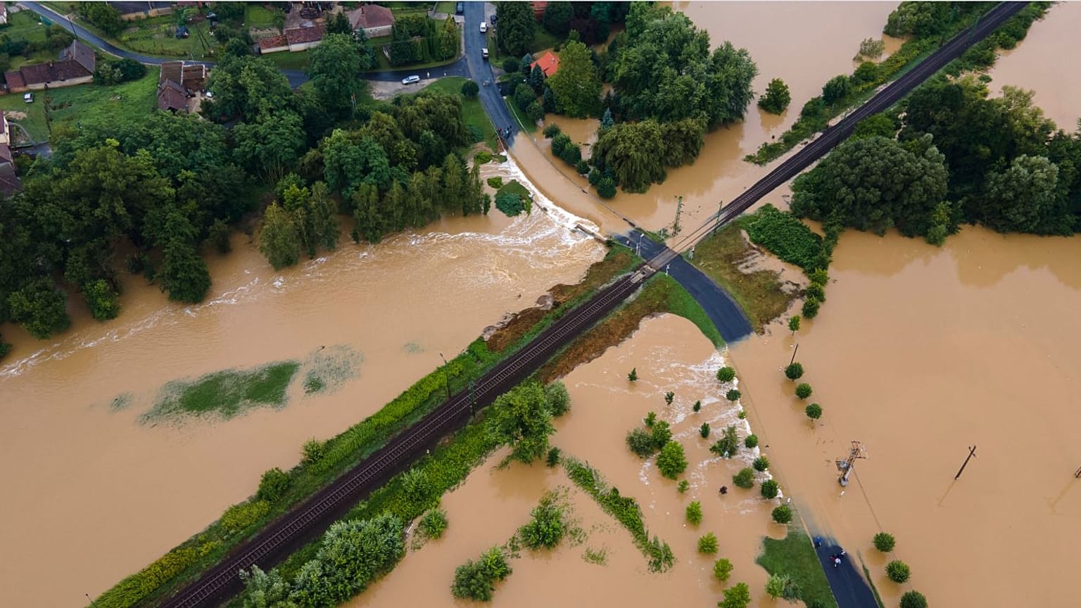 A nagy esőzés miatt vízzel elárasztott és megrongálódott út Zalaszentjakabon 2020. július 25-én. Középen a Budapest-Nagykanizsa vasútvonal része látható.