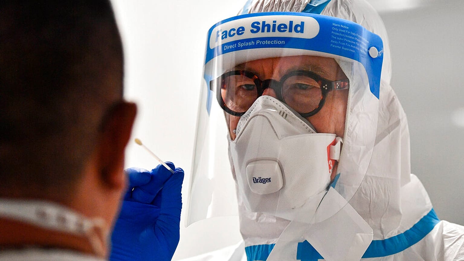 A doctor takes a COVID-19 test from a passenger who arrived at the airport in Duesseldorf, Germany, Monday, July 27, 2020