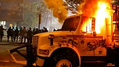 Police stand in front of a utility vehicle that was set on fire by protesters during a demonstration in Richmond, Virginia, July 25, 2020