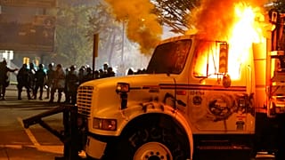 Police stand in front of a utility vehicle that was set on fire by protesters during a demonstration in Richmond, Virginia, July 25, 2020