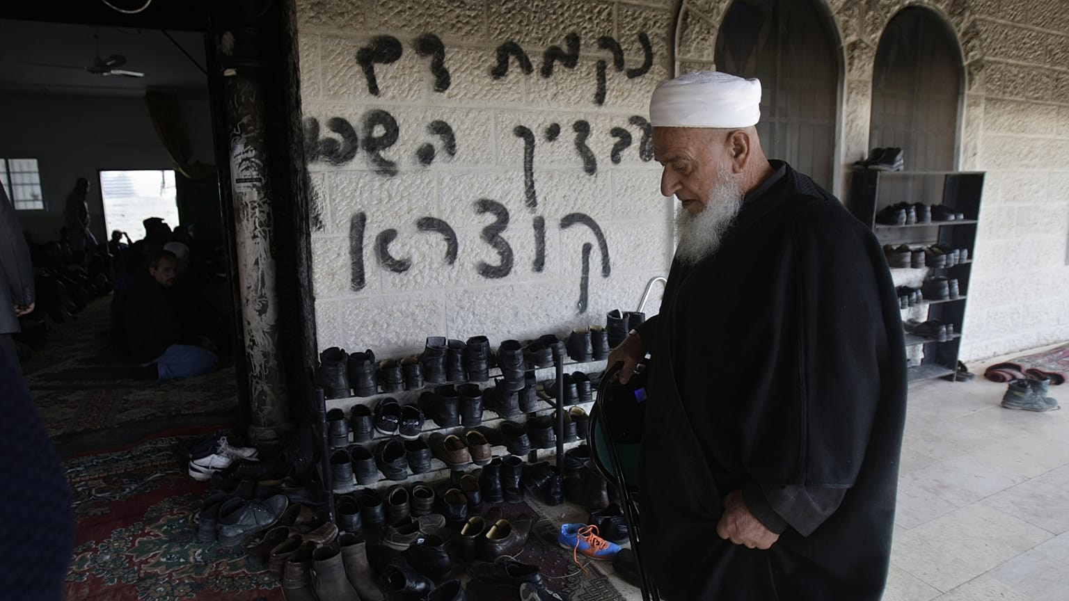 من الأرشيف: رجل فلسطيني يزور مسجدًا متضررًا في قرية دير استيا بالضفة الغربية حيث اشتعلت النيران في باب المسجد 