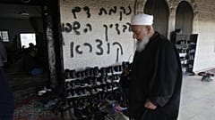 من الأرشيف: رجل فلسطيني يزور مسجدًا متضررًا في قرية دير استيا بالضفة الغربية حيث اشتعلت النيران في باب المسجد 