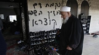 من الأرشيف: رجل فلسطيني يزور مسجدًا متضررًا في قرية دير استيا بالضفة الغربية حيث اشتعلت النيران في باب المسجد