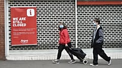 Members of the public walk past a closed shop in Leicester city centre, England