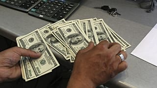 A currency exchange bureau worker, counts US dollars, in downtown Tehran, Iran