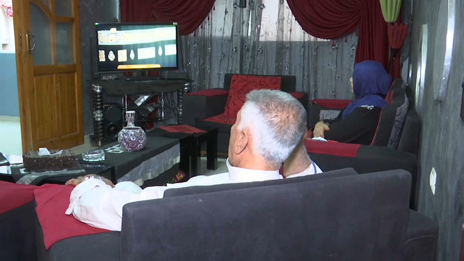 فؤاد أبو صافي وزوجته اعتدال أبو صافي يتابعان الحج عبر شاشة النلفاز من بيتهما في غزة