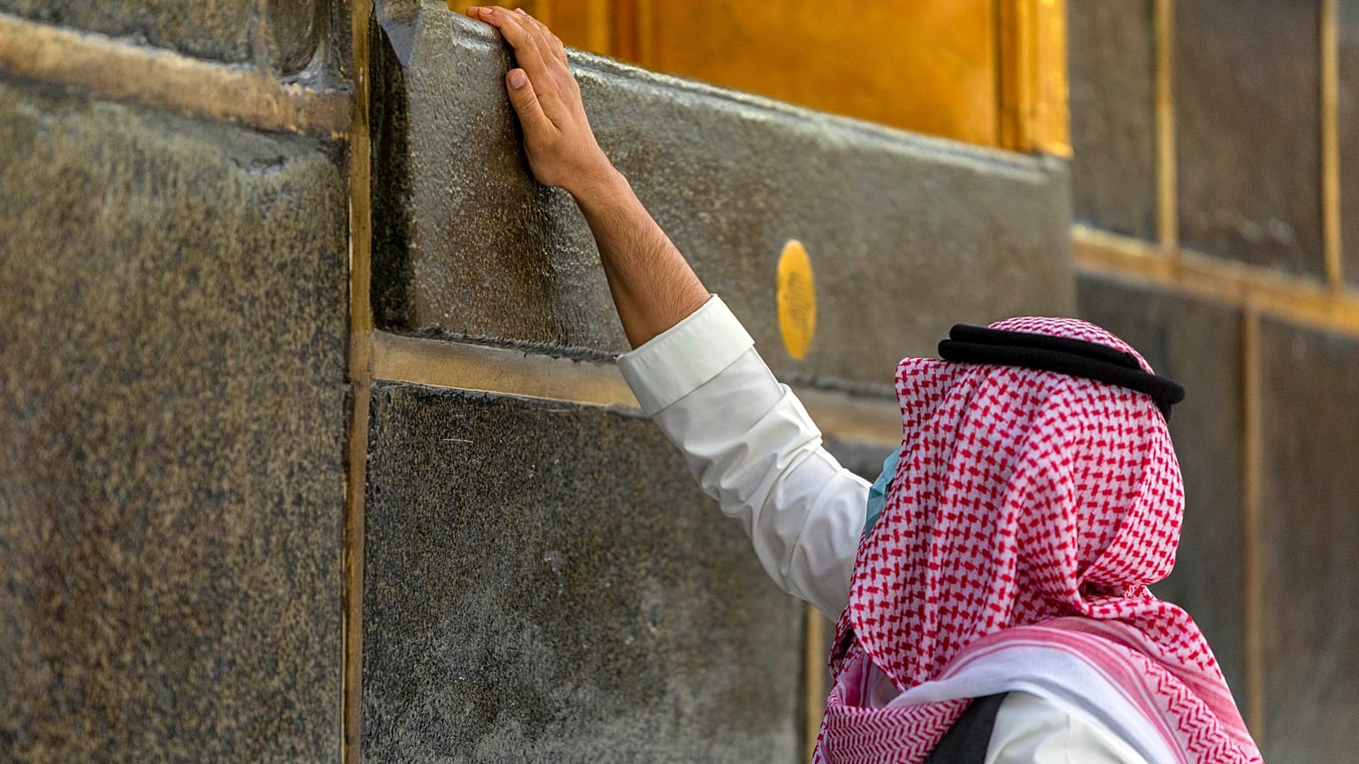 أحد المصلين يلمس جدار الكعبة 