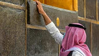 أحد المصلين يلمس جدار الكعبة 