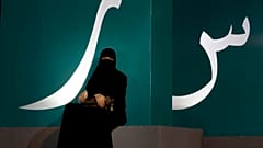 مرأة تجلس عند لافتة مكتوبة بحروف عربية خلال حدث ثقافي  حديقة الواجهة المائية بجدة/ المملكة العربية السعودية