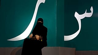 مرأة تجلس عند لافتة مكتوبة بحروف عربية خلال حدث ثقافي حديقة الواجهة المائية بجدة/ المملكة العربية السعودية