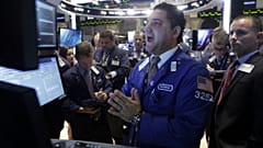 Specialist Ronnie Howard, center, calls out prices as he works at his post on the floor of the New York Stock Exchange