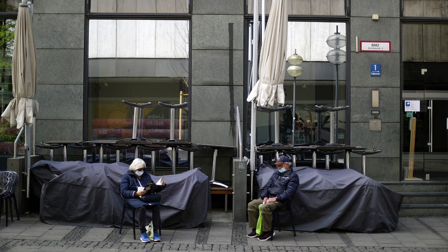 An elderly couple sit outside a closed bar in Munich, Germany