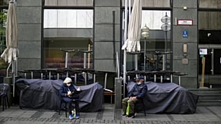 An elderly couple sit outside a closed bar in Munich, Germany