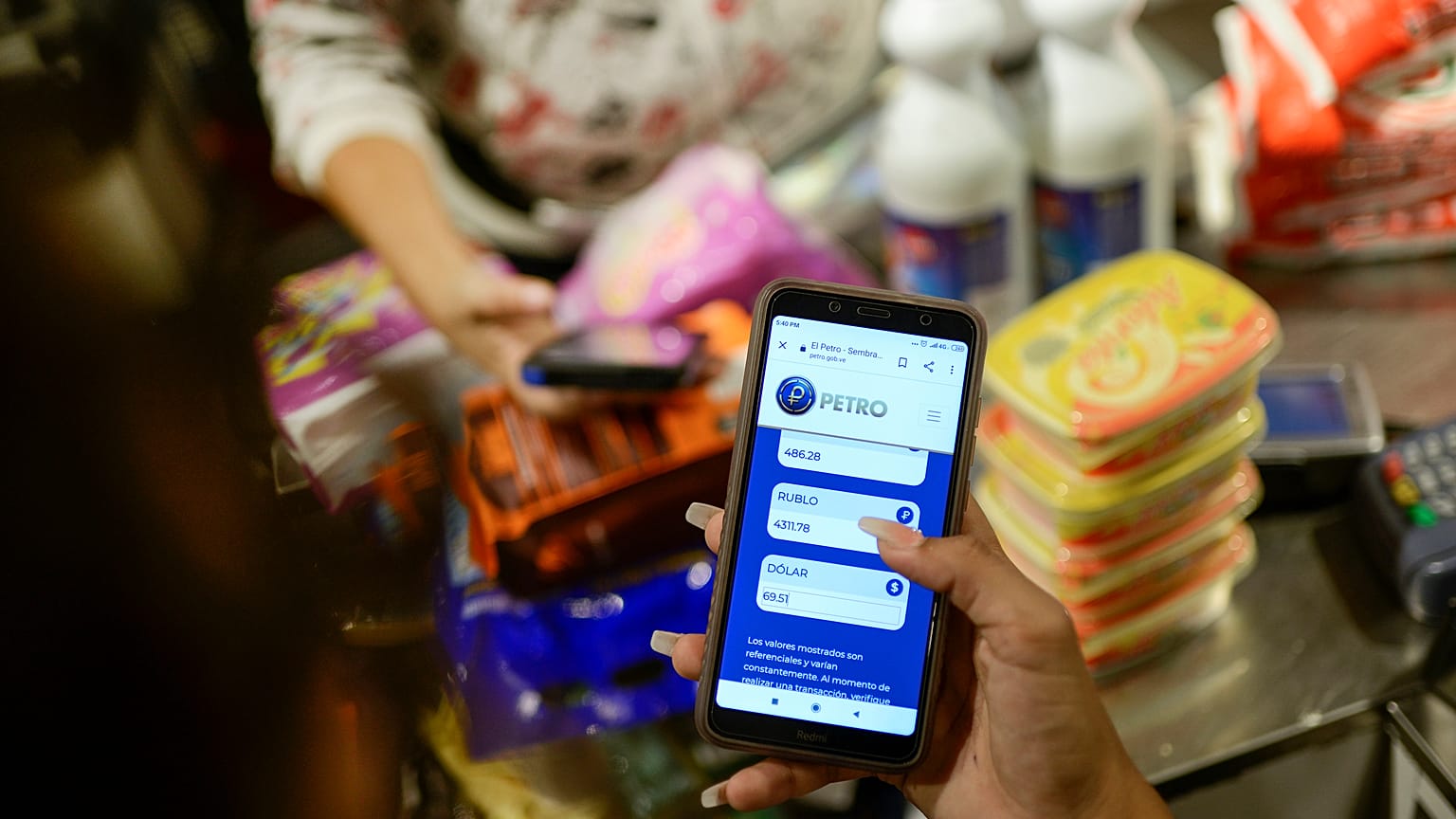 Una empleada muestra su teléfono móvil mientras calcula el monto de la compra en Petros en una tienda  donde se acepta la criptomoneda venezolana, en Caracas, Venezuela.