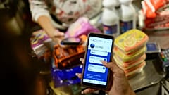 Una empleada muestra su teléfono móvil mientras calcula el monto de la compra en Petros en una tienda  donde se acepta la criptomoneda venezolana, en Caracas, Venezuela.