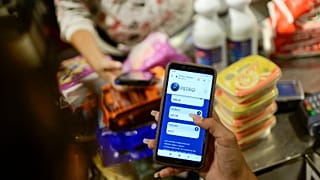 Una empleada muestra su teléfono móvil mientras calcula el monto de la compra en Petros en una tienda  donde se acepta la criptomoneda venezolana, en Caracas, Venezuela.