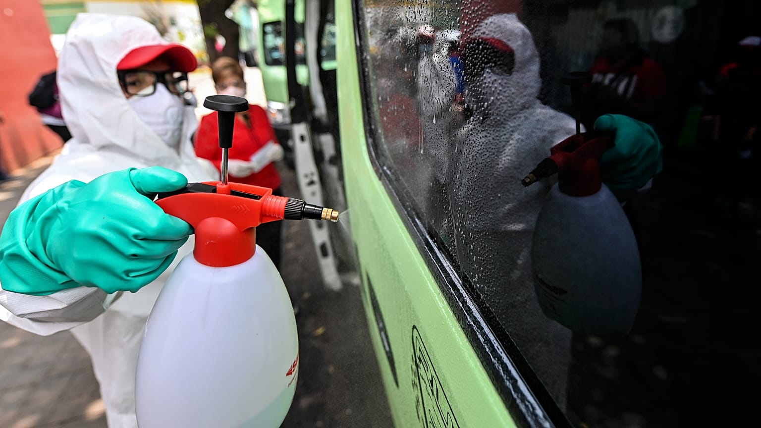 Un empleado con equipamiento de protección limpia un vehículo de transporte público en Ciudad de México
