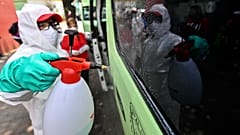 Un empleado con equipamiento de protección limpia un vehículo de transporte público en Ciudad de México