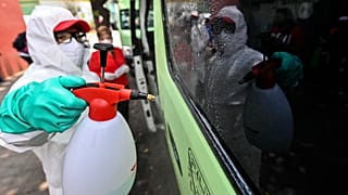 Un empleado con equipamiento de protección limpia un vehículo de transporte público en Ciudad de México