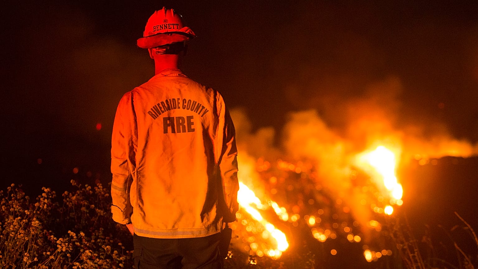 Un bombero observa un incendio de matorrales en el incendio de Apple en Banning, California, el sábado 1 de agosto de 2020.