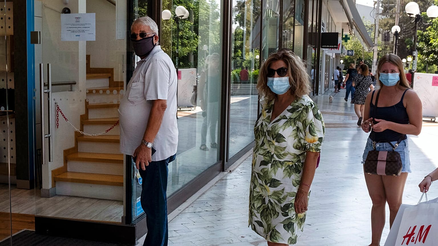 Πολίτες φορούν μάσκα και περιμένουν στην ουρά