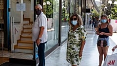 Πολίτες φορούν μάσκα και περιμένουν στην ουρά