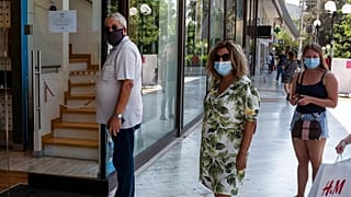 Πολίτες φορούν μάσκα και περιμένουν στην ουρά