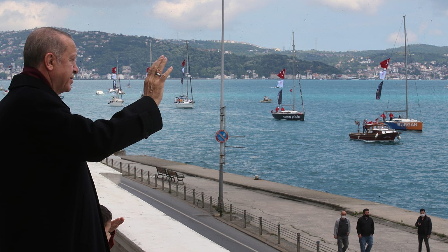 O T. Ερντογάν χαιρετά πλοία διακοσμημένα με την τουρκική σημαία κατά τους εορτασμούς για την κατάκτηση της Κωνσταντινούπολης