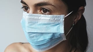A woman wears a disposable face mask.