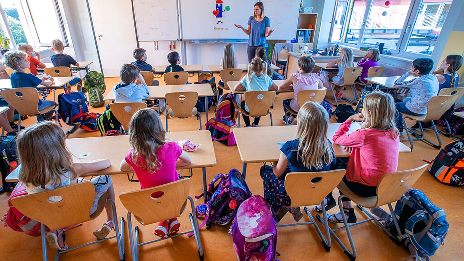 Teacher Francie Keller welcomes the pupils of class 3c in the Lankow primary school to the first school day in Schwerin, Germany, Monday, Aug. 3, 2020.