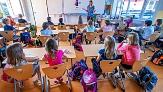 Teacher Francie Keller welcomes the pupils of class 3c in the Lankow primary school to the first school day in Schwerin, Germany, Monday, Aug. 3, 2020.