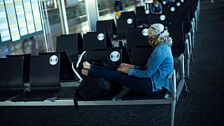 Una pasajera, con una máscara facial para protegerse de la propagación del coronavirus, se sienta antes de embarcar en su vuelo 