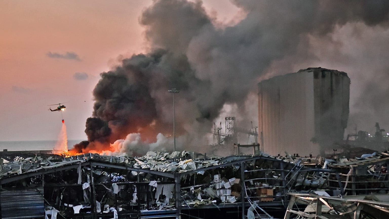 A helicopter puts out a fire at the scene of an explosion at the port of Lebanon's capital Beirut on August 4, 2020. STR / AFP