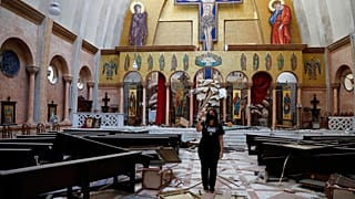Nő készít képeket egy megsérült keresztény templomban szerdán