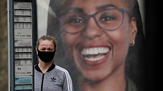 Una mujer con mascarilla espera junto a una parada de autobús en el Reino Unido