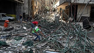 Workers remove rubble from damaged buildings near the site of an explosion that hit the seaport of Beirut.