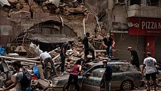 أشخاص يزيلون حطام منزل دمره انفجار الثلاثاء في ميناء بيروت، لبنان، وفرق الإنقاذ تبحث عن جثث بين الأنقاض